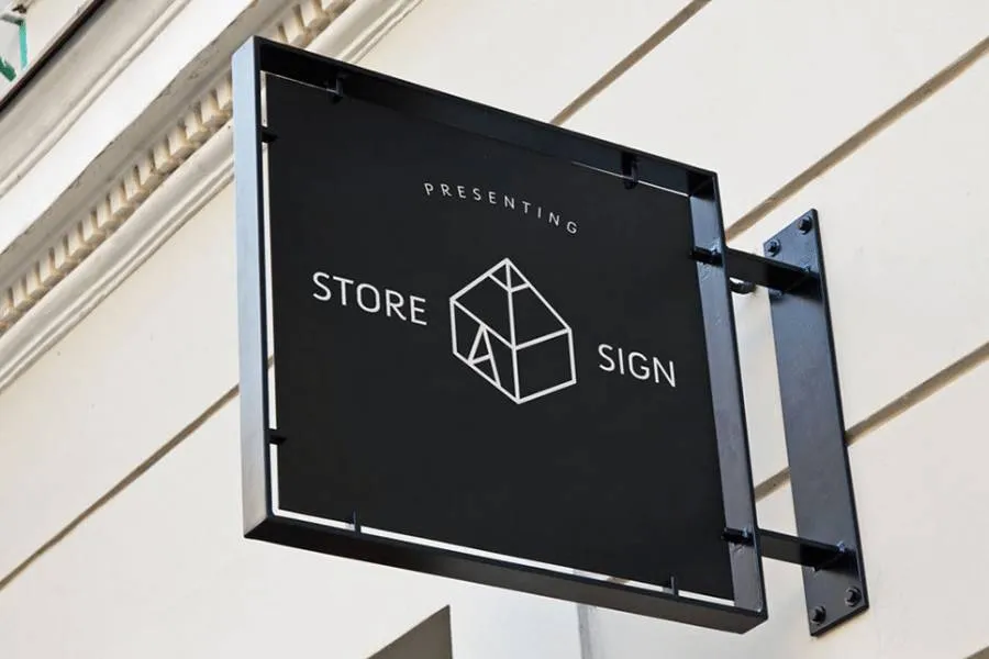 A black square blade sign on a black frame installed on side of a wall.