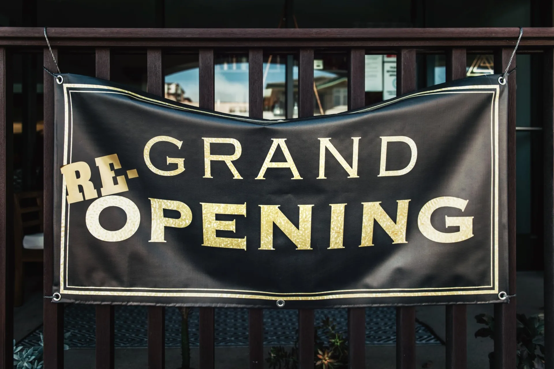 A banner that says grand reopening, installed on wood railings.