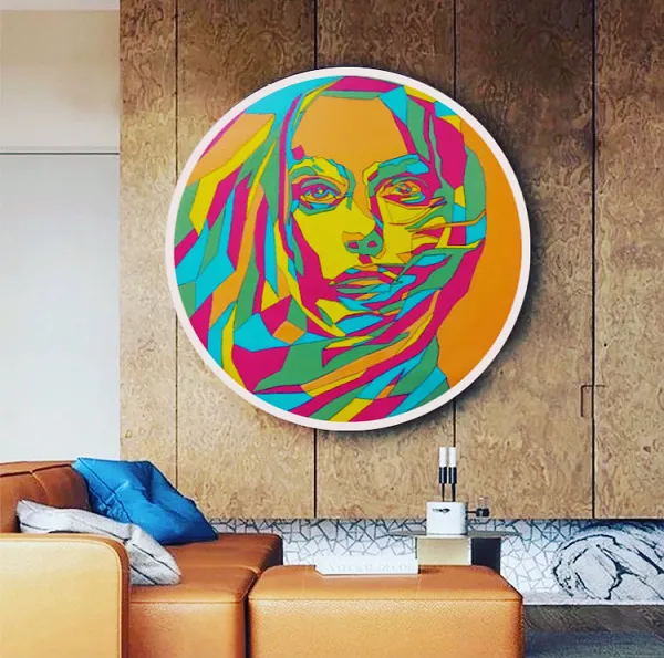 A round sign with a image of a woman's face in a colourful and artistic style. Installed on a wood panel backing.