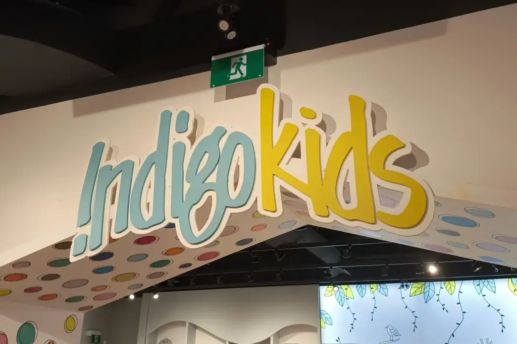 3D letter sign that says "indigo kids" installed on the wall above an arch